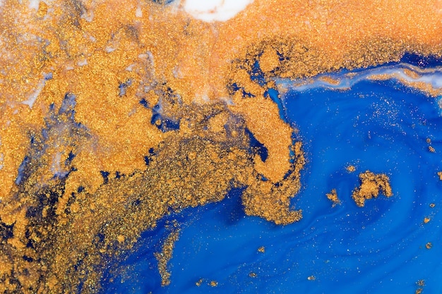 Luxury fluid art painting background. Spilled blue, white and gold acrylic paint. Liquid marble. Alcohol ink splash.