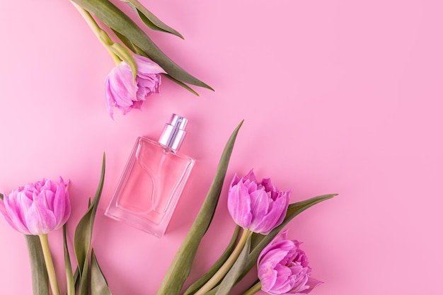 luxury glass bottle of womens perfume or cosmetic spray on pink background with spring flowers Perfume and beauty concept A copy space