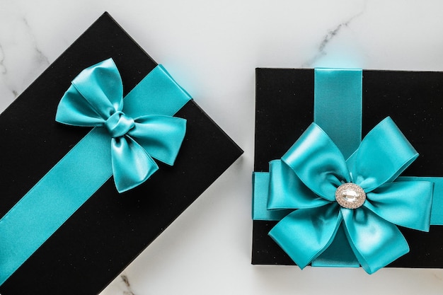 Luxury holiday gifts with emerald silk ribbon and bow on marble background