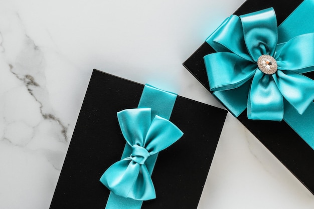 Luxury holiday gifts with emerald silk ribbon and bow on marble background