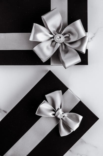 Luxury holiday gifts with silver silk ribbon and bow on marble background