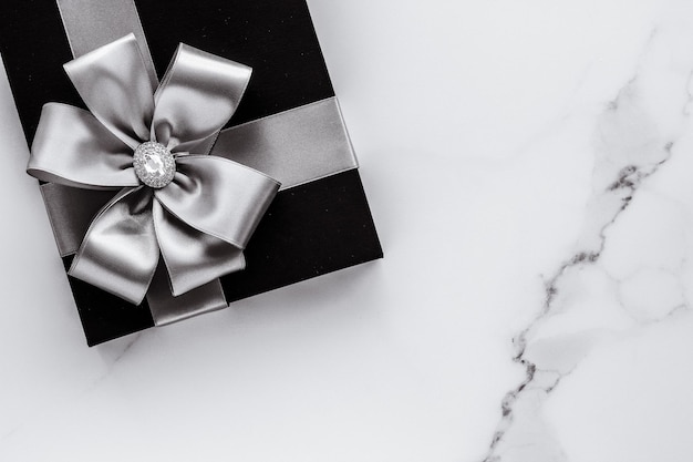 Luxury holiday gifts with silver silk ribbon and bow on marble background