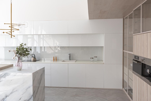 Luxury interior design of modern trendy snow white kitchen in minimalistic style with island and two bar stools huge windows to the floor and a glass rack for dishes