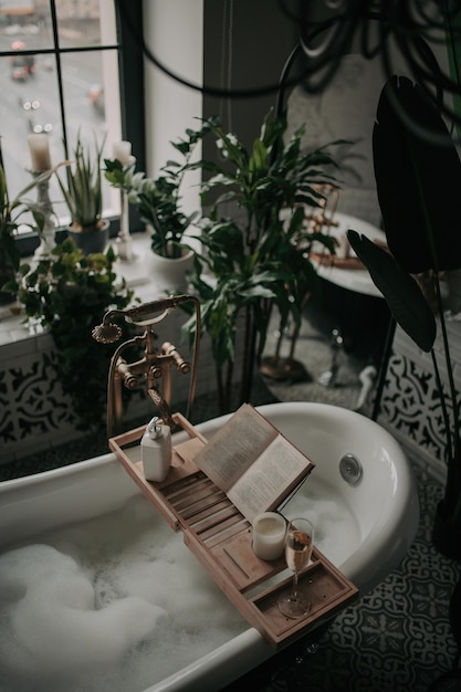 Photo luxury interior of eco style modern bathroom with oval bathtub and book on bamboo wood tray