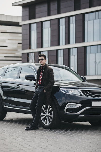 Luxury lifestyles. Handsome young man in business wear standing near his car