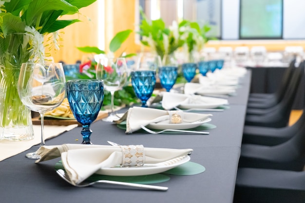 Luxury Lunch or Dinner set on the long table pattern with a black cover table with flower decoration.