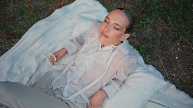 Luxury model lying green grass with wine glass top view chic woman closing eyes