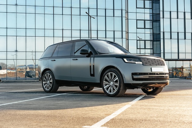 Photo luxury suv car parked against a background of glass building