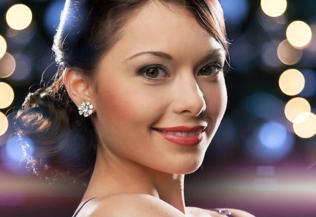 luxury, vip, nightlife, party concept - beautiful woman in evening dress wearing diamond earrings