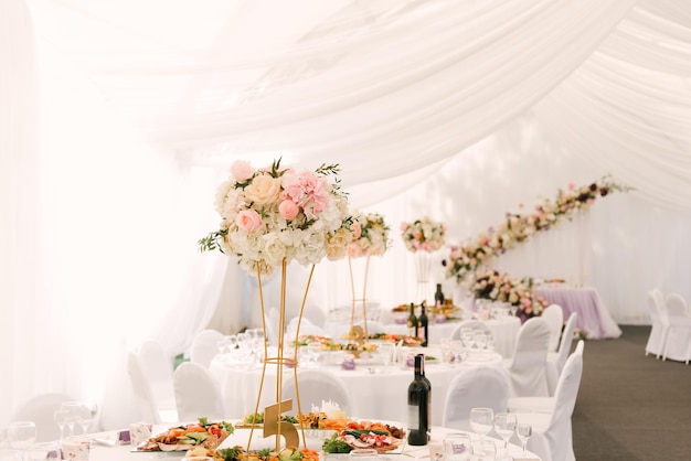 Luxury wedding dinner in a large beautiful tent beautiful decor for the wedding of the white hall decorated with flowers