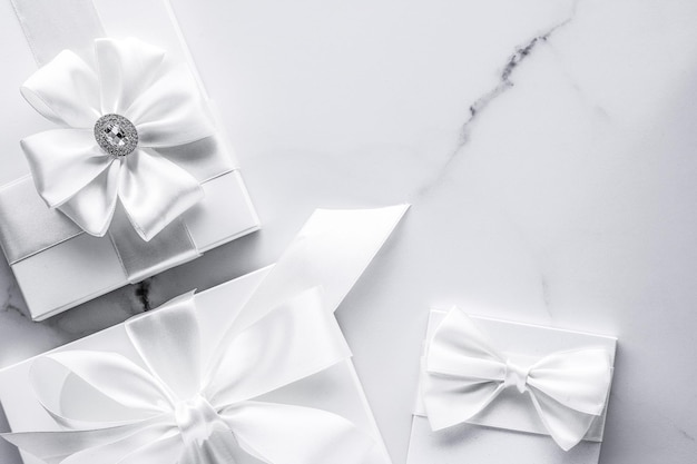 Luxury wedding gifts with silk bow and ribbons on marble background