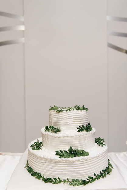 Luxury wedding tiered white cake decorated with flowers photo at night on the background of lights