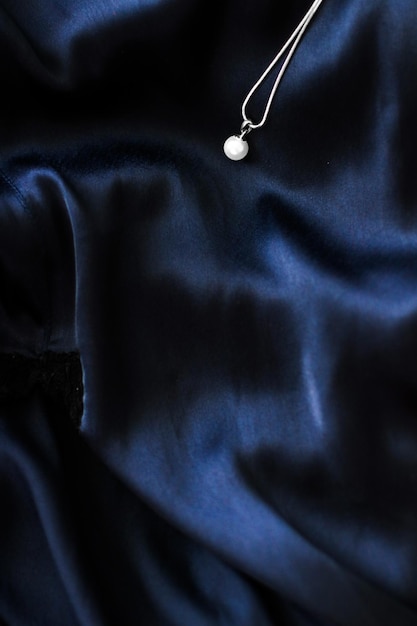 Luxury white gold pearl necklace on dark blue silk background holiday glamour jewelery present