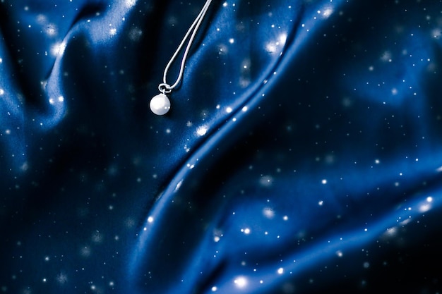 Luxury white gold pearl necklace on dark blue silk holiday winter magic jewelery present