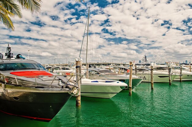 Luxury yachts docked in the port in bay at sunny day with clouds on blue sky in Miami