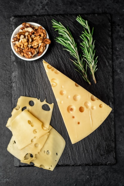 Maasdam cheese with walnut and rosemary on stone table