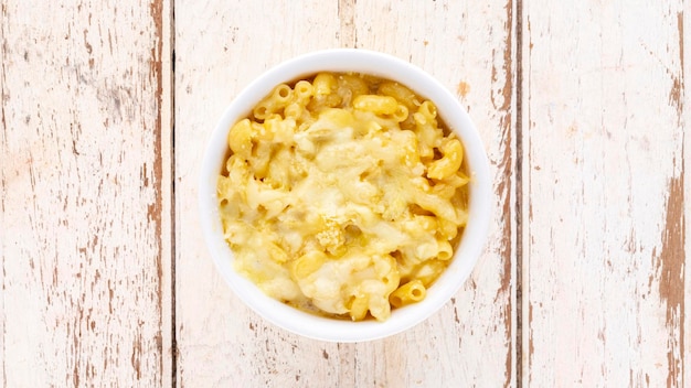 Mac and Cheese macaroni pasta with cheese in ceramic bowl on white old wood texture background top view flat lay light and airy food photography