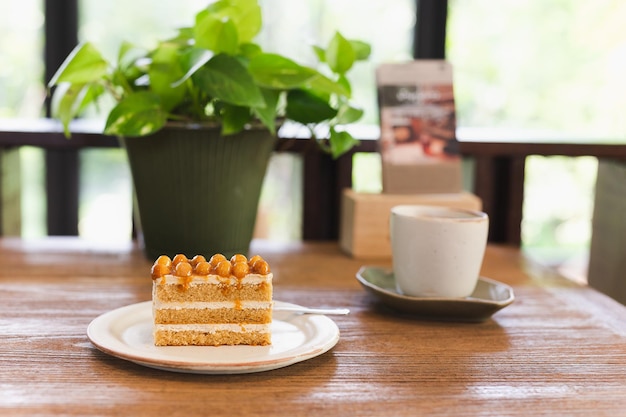 Macadamia caramel cake topping with macadamia nuts with coffee on table