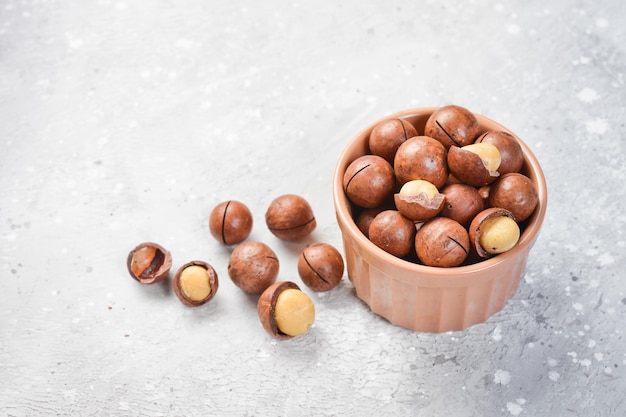 Macadamia nut Macadamia nuts in a shell in a bowl On a stone background Macadamia nuts are rich in various trace elements and vitamins