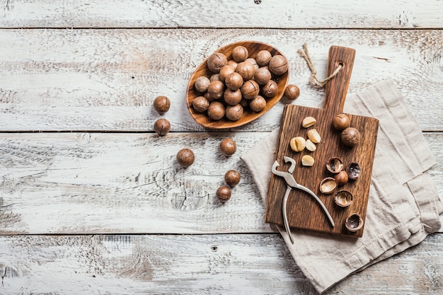 Macadamia nuts on cutting board over white wooden table