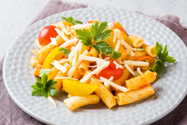 Macaroni, pasta in tomato sauce and cheese in a plate on a woode