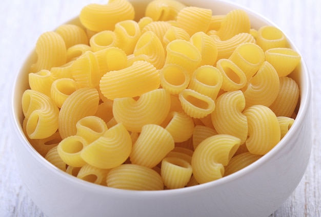 Macaroni in white bowl on wooden table