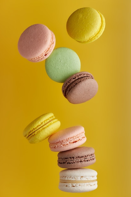 Macaroon. Colorful cake macaron with pastel tones fall at the stack macaroon on an  yellow surface. Top view of almond cookies.