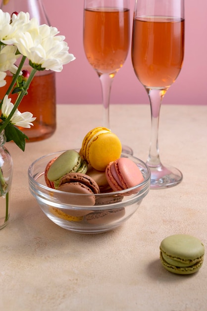 Macaroons colorful cookies in glass bowl served with champagne drink Macarons french sweet dessert pink background