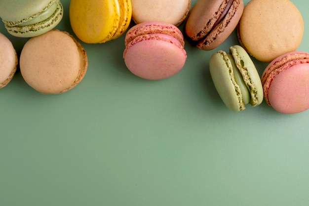 Macaroons colorful cookies Macarons in bowl french sweet dessert top view green background Copy space