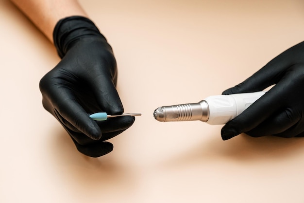 A machine for professional hardware manicure in a woman's hand on a light background Equipment for the nail service master Cosmetic procedures