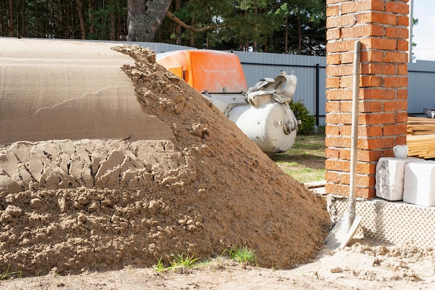 Machine with mixer isinstallation for feeding cement mixture for pouring semidry floor screed in house Construction site with slide of sand preparation for leveling the rough floor of cottage