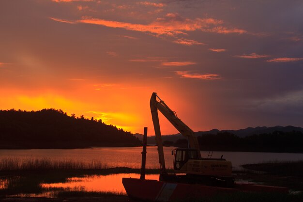 machine in worksite near lake on sunset