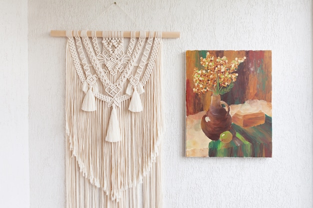 Macrame. Decoration for the interior. Interior design  with beige beautiful macrame and canvas painting. Concept of cozy home decor.