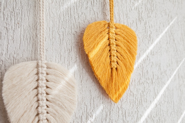 Photo macrame leaves wall hanging in yellow, white and green  and natural color on the wooden stick. cotton rope decor macrameto make your room more cozy and unique. copy space