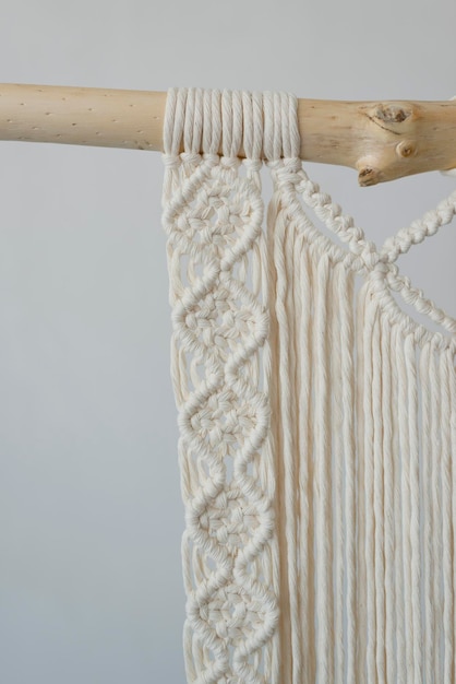 The macrame panel element hangs on a wooden base