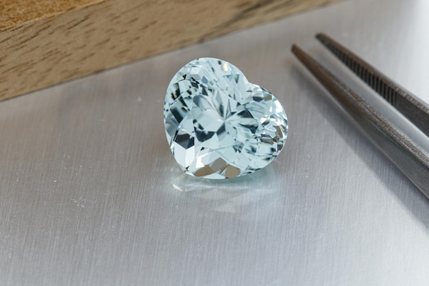 Macro mineral faceted stone aquamarine with tweezers on a gray background