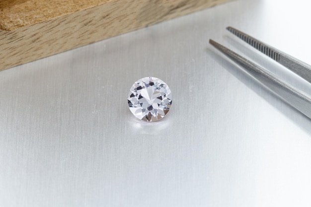 Macro mineral faceted stone Morganite with tweezers on a gray background