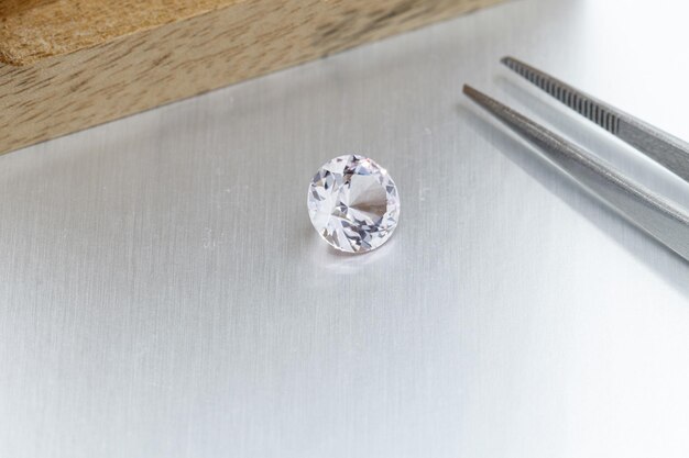 Macro mineral faceted stone Morganite with tweezers on a gray background