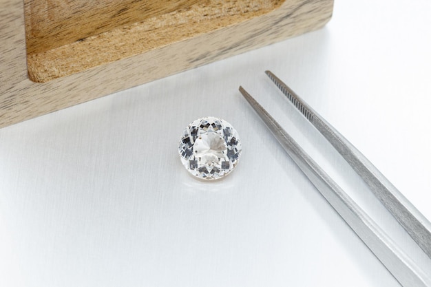 Macro mineral faceted stone Morganite with tweezers on a gray background