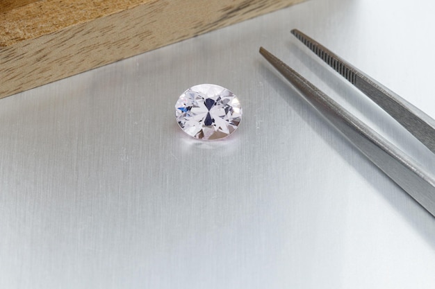 Macro mineral faceted stone Morganite with tweezers on a gray background