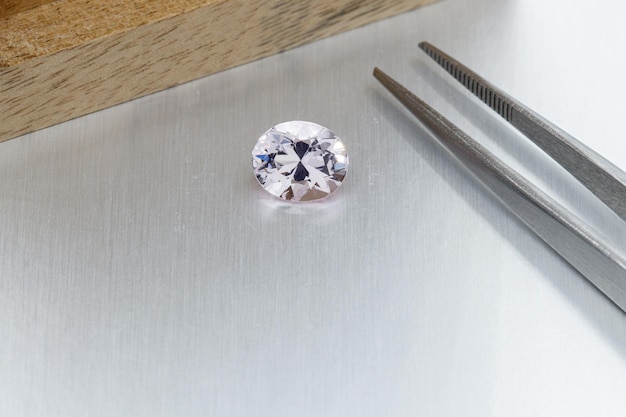 Macro mineral faceted stone Morganite with tweezers on a gray background