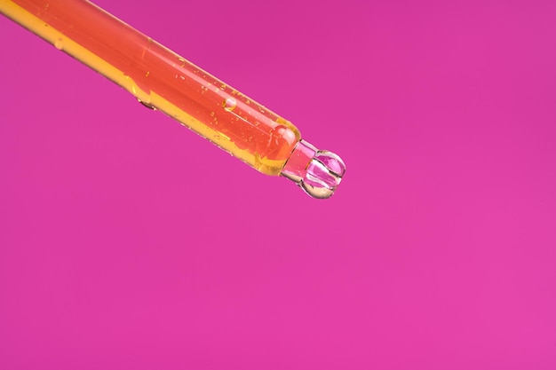 Macro photo of cosmetic or essential oil serum dropping from glass dropper