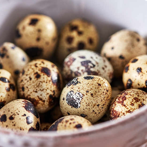 Macro photo of organic quail eggs in a white plate on a wooden table. Healthy food. Top view