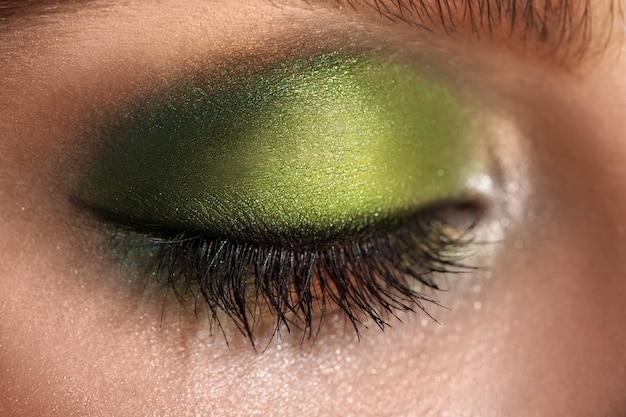 Photo macro picture of closed eye with green colors makeup. studio shot. horizontal.