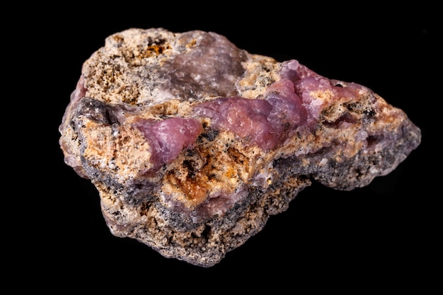 Macro pink Smithsonite mineral stone on microcline on black background