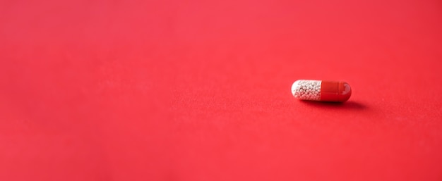 Macro of red capsules on red background. Copy space. Bunch of drugs, cold flu treatment. Banner.