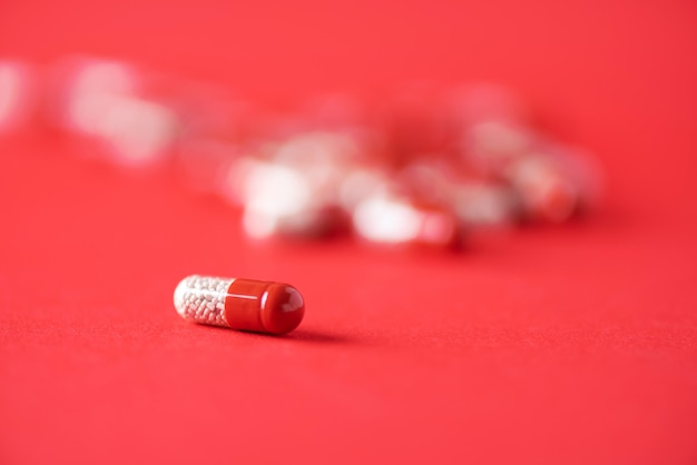 Macro of red capsules on red background. Copy space. Bunch of drugs, cold flu treatment.