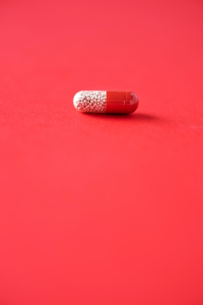 Macro of red capsules on red background. Copy space. Bunch of drugs, cold flu treatment.