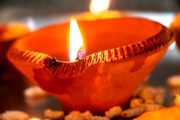 Macro shots of diyas being lit by hand or candle for the hindu religious festival of Diwali. These colorful earthern pots hold oil and a cotton wick to light