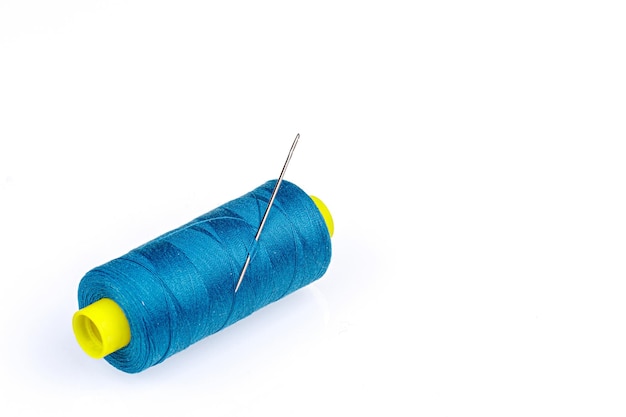 Macro skein of blue thread with a needle on a white background